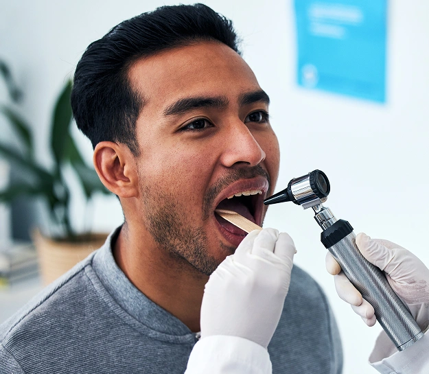 Man receiving dental examination with mirror and tool in modern dental office setting.