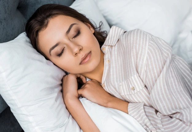 Woman peacefully sleeping on pillow, promoting rest and dental health awareness.